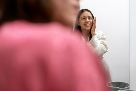 Woman applying makeup while getting ready with friend before party - Powered by Adobe
