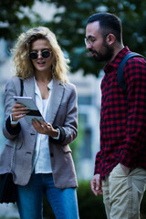 Two young professionals in a productive outdoor meeting while discussing digital content on a...