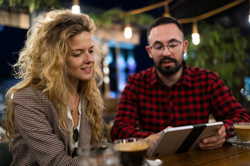 Young professionals having a casual meeting over coffee in a creative café setting, discussing...
