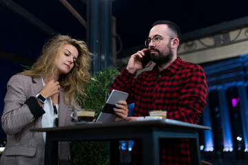 Casual evening meeting with two colleagues discussing business ideas over coffee at an outdoor cafe