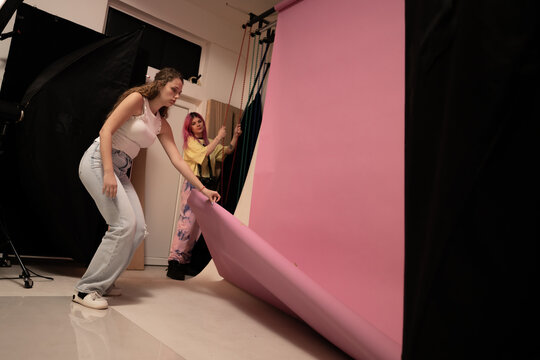 Photographers Preparing Studio With Pink Backdrop for Creative Photoshoot - Powered by Adobe