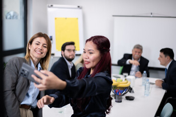 Work team taking a selfie in a modern office setting during a meeting
