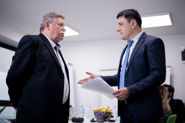 Two business professionals engaged in a conversation during a meeting in a modern office setting