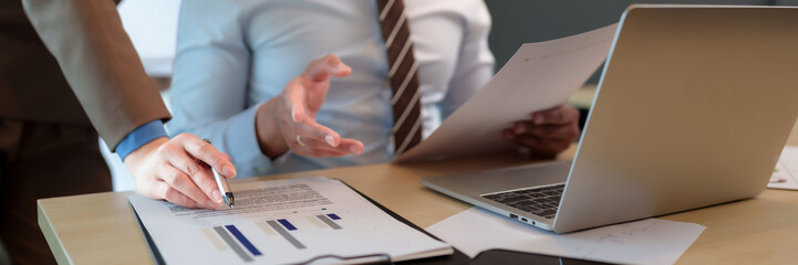 Business professionals hands analyzing financial data report chart on documents using laptop during meeting at office desk collaborative work