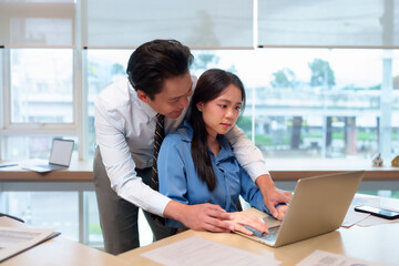 Asian adult man touching hand Asian adult woman working laptop inappropriate behavior workplace office environment