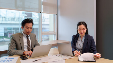 Asian business man woman working together analyzing reports discussing strategy modern office meeting room