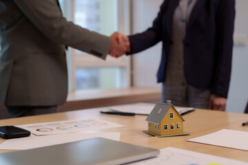 Business adults hands shaking real estate property deal closing agreement office meeting house model charts documents finance investment