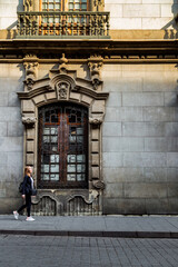 Young woman walking by colonial window in Mexico City historic center