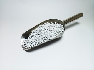 White plastic masterbatch, polymer carries colorful pigments with small scoops poured into a white...
