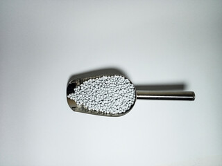 plastic masterbatch, polymer carries colorful pigments with small scoops poured into a white...