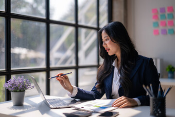 A woman in a business suit is sitting at a desk with a laptop