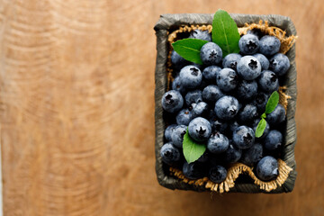 Ripe blueberries in wicker basket on wooden table.