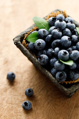 Ripe blueberries in wicker basket on wooden table.