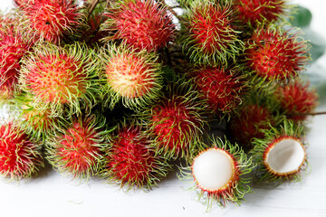 Fresh rambutan fruit on white wooden table.