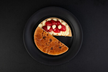 Cake with fruit on a black plate, isolated on black background