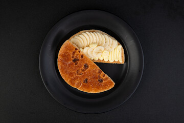 Banana tart on a black plate, top view