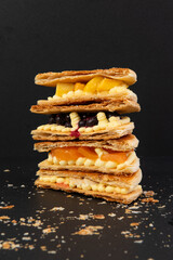 Delicious waffles with fruits on a black background, close-up