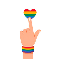 A hand with a pride bracelet touches a rainbow colored heart, a powerful symbol for love, equality, freedom, and rights.