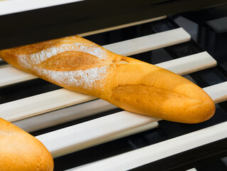 Freshly baked baguette resting on wooden rack in artisan bakery creates a delightful anticipation...