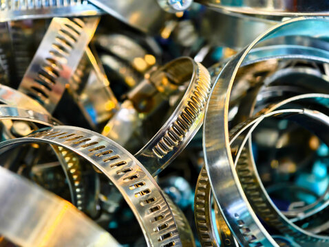 Metal clamps and fasteners piled together in a workshop setting during bright daylight hours