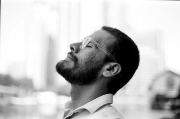 Bearded man wearing glasses relaxing with eyes closed in monochrome