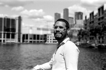 Bearded man wearing glasses posing in rotterdam city center with film grain