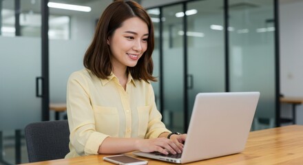 Obraz premium Photo of smiling woman working on a laptop in an office