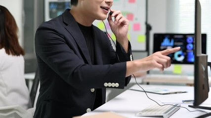 Asian businessman working as a telemarketer wearing a headset. - Powered by Adobe