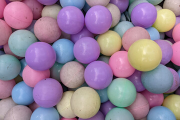 full-frame pile of numerous pastel-colored plastic balls, showing some visible dirt and wear, creating a playful yet slightly used texture.