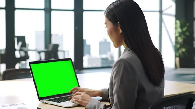 businesswoman working on laptop in the office green screen office environment 