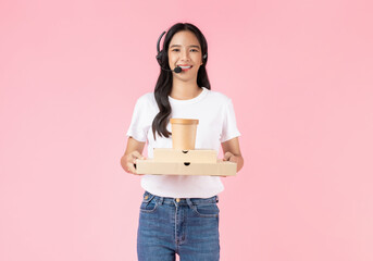 Studio shot of Beautiful Asian woman holding pizza boxes and consultant wearing microphone headset of customer support phone operator with isolated on pink background.