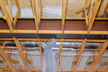 Carpenter is repairing wooden beams spray foam insulation in residential attic thermal barrier