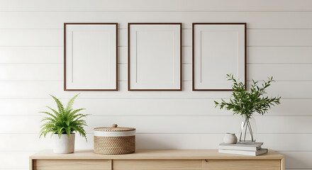 Fototapeta premium Three blank frames displayed above a wooden table with greenery and decorative accessories