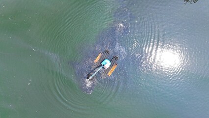 View from above of an excavator dredging a lake on the riverbank in North Jakarta