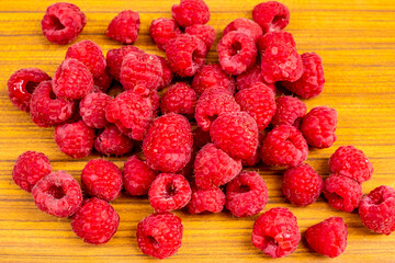 Pile of ripe raspberries isolated on wooden background. Raspberries on top view image.