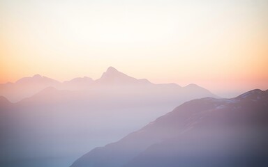 Fototapeta premium Misty mountain peaks at sunrise with pastel sky haze