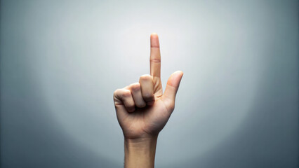 Hand raised with one finger pointing upwards against a soft background.