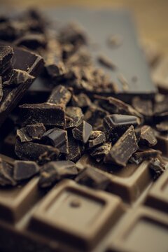Naklejki 3D render is showing broken dark chocolate bar on wooden tabletop with shards and cocoa dust