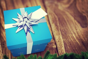 Flat-design blue gift box featuring white ribbon, silver bow is sitting on table, with pine branch