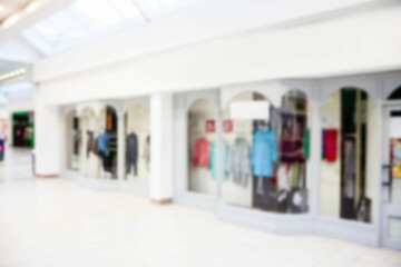row of arched glass storefronts is showcasing clothing racks and mannequins in flat design