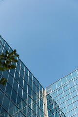 Low angle view of glass office building against blue sky