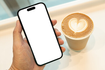 Hand Holding Smartphone with Blank Screen and Coffee Cup with Heart Latte Art. a blank white...