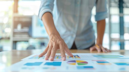Fototapeta premium A person's hand touching a document with colorful charts and graphs on it.