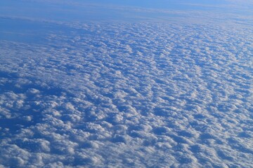 High-angle view of a vast expanse of puffy white clouds,  covering a cerulean sky