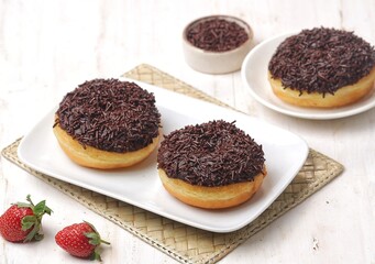 Donuts or doughnuts or donat coklat with chocolate glazed and chocolate sprinkles. served on white...