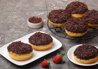 Donuts or doughnuts or donat coklat with chocolate glazed and chocolate sprinkles. served on white plate. donat coklat homemade. selected focus