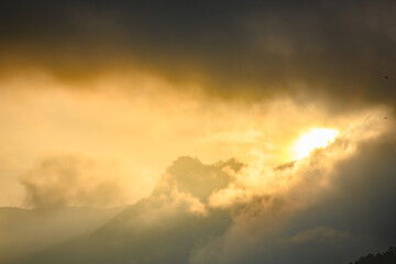 Golden light shines through the clouds and mountains.