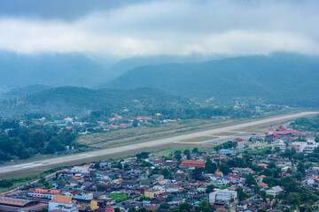 A runway surrounded by the city, mountains, and mist.