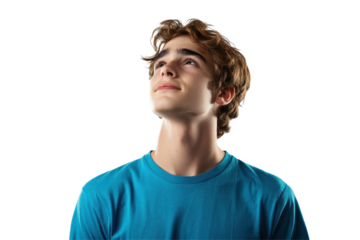 Young man in a blue t-shirt gazes upward with a dreamy expression in a softly lit environment, reflecting on thoughts and dreams during a serene moment