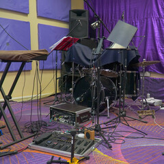 View of the interior of the rehearsal room. View of drums, keyboards and guitar in a case